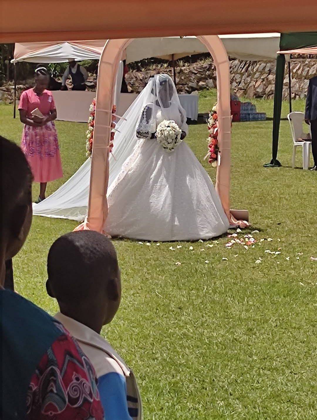 A bride walking down the aisle beneath a floral arch