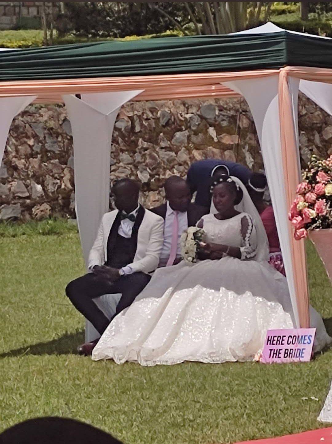 A bride and groom seated under a decorated garden gazebo